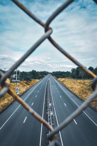 Road against sky seen through mesh wire