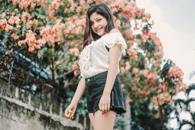 Portrait of smiling young woman standing against trees