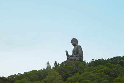 Man sitting on smart phone against clear sky