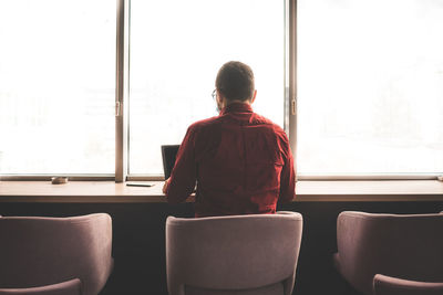 Rear view of man sitting at home