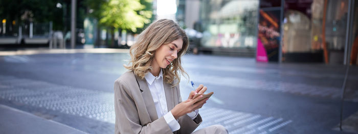 Young woman using mobile phone in city