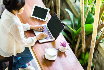 Midsection of woman holding mobile phone while sitting on table