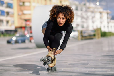 Portrait of woman roller skating on sidewalk in city