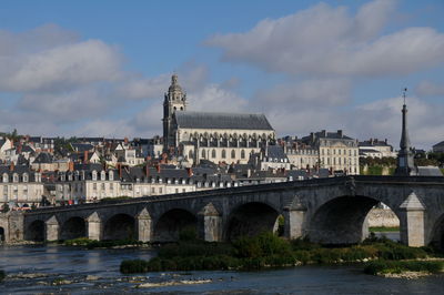 Arch bridge over river against buildings in city