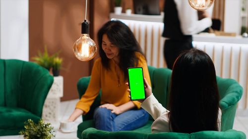 Friends using mobile phone at home