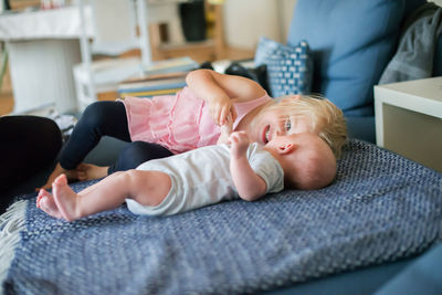 Sister with baby boy relaxing on bed at home