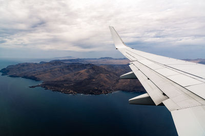 Cropped airplane flying over sea against sky