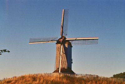 Low angle view of traditional windmill on field against clear sky