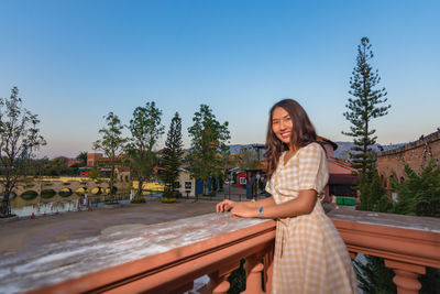 Young woman sitting against built structure against clear sky