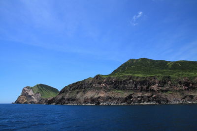 Scenic view of sea and mountains against blue sky