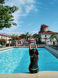 Rear view of man in swimming pool against sky