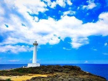 Lighthouse by sea against sky