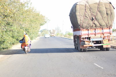 Rear view of man riding motorcycle on road