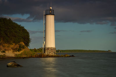 Lighthouse by sea against sky