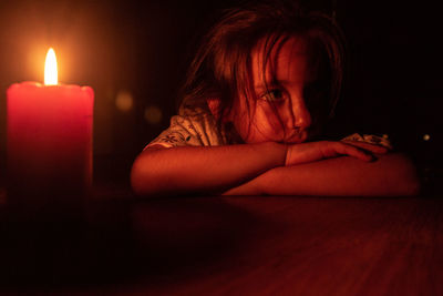 Close-up of sad girl by candle at home
