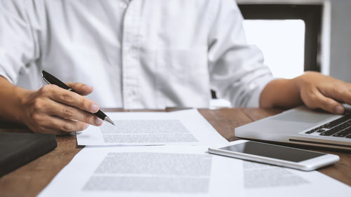 Midsection of man using mobile phone on table