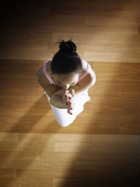 Directly above shot of woman practicing yoga on hardwood floor