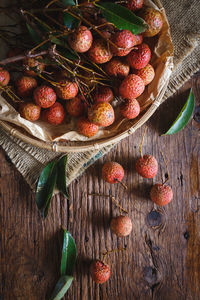 High angle view of lychees and wicker basket on wooden table