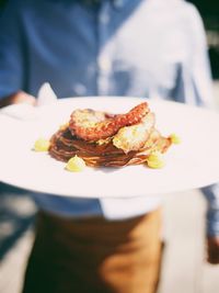 Midsection of man holding plate with food while standing outdoors