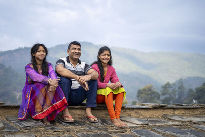 Indian father sitting with his daughters and smiling, happy family concept.