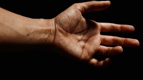 Cropped hand of person gesturing against black background