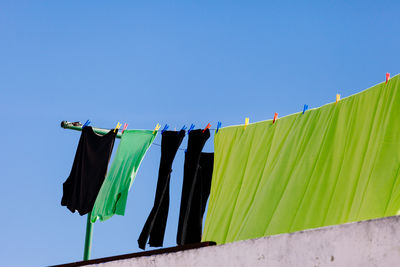 Low angle view of clothes drying at building terrace against clear sky