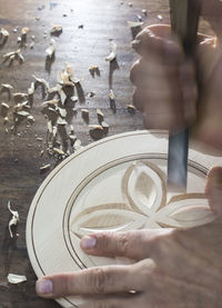 Cropped hands of artist carving wood in workshop