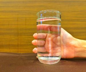 Close-up of hand holding glass of water on table