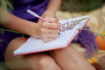 Woman writing in notebook near lupines. closeness to nature, self-discovery.  relax and welll-being