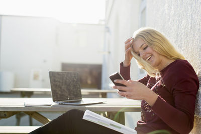 Happy teenage girl using mobile phone at picnic table