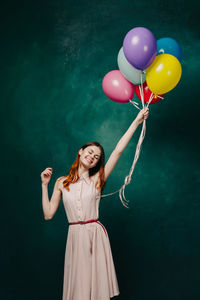 Full length of smiling young woman holding balloons