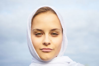 Close-up portrait of a smiling young woman against sky