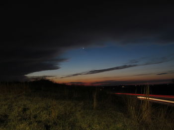 Illuminated field against sky at night