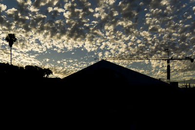 Low angle view of silhouette house against sky at sunset