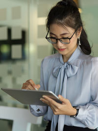 Woman using digital tablet while sitting in office