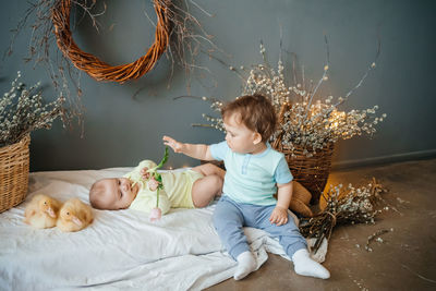 Two babies with small goslings eco style grey background wicker basket willow