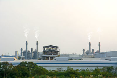 Smoke emitting from factory against sky