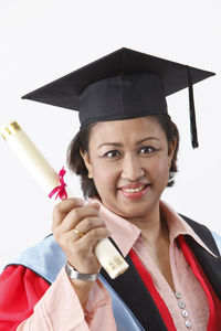 Happy woman in graduation gown against white background