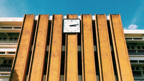 Low angle view of clock on building against sky