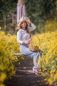 Full length of woman holding yellow flowers