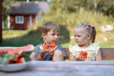 Cute caucasian children eating watermelon in countryside