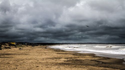 Scenic view of beach against cloudy sky