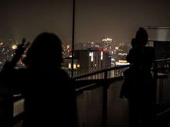 Rear view of silhouette man looking through window at night