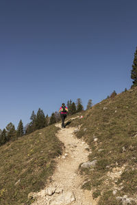 Rear view of people walking on mountain against clear sky