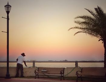 Silhouette man standing on beach against sky during sunset