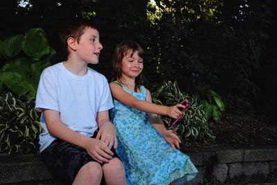 Full length of happy girl sitting outdoors