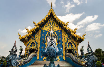 Low angle view of statue by building against sky