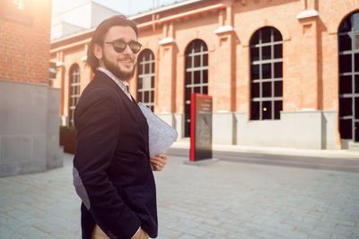 Side view of man standing against building