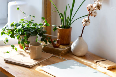 Freelancer working place. wooden desktop, laptop, vase, houseplants, sketchbook.