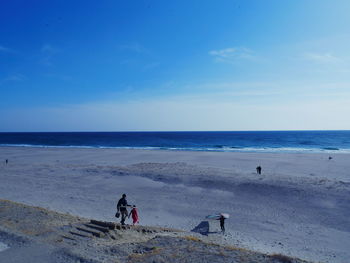 People at beach against blue sky